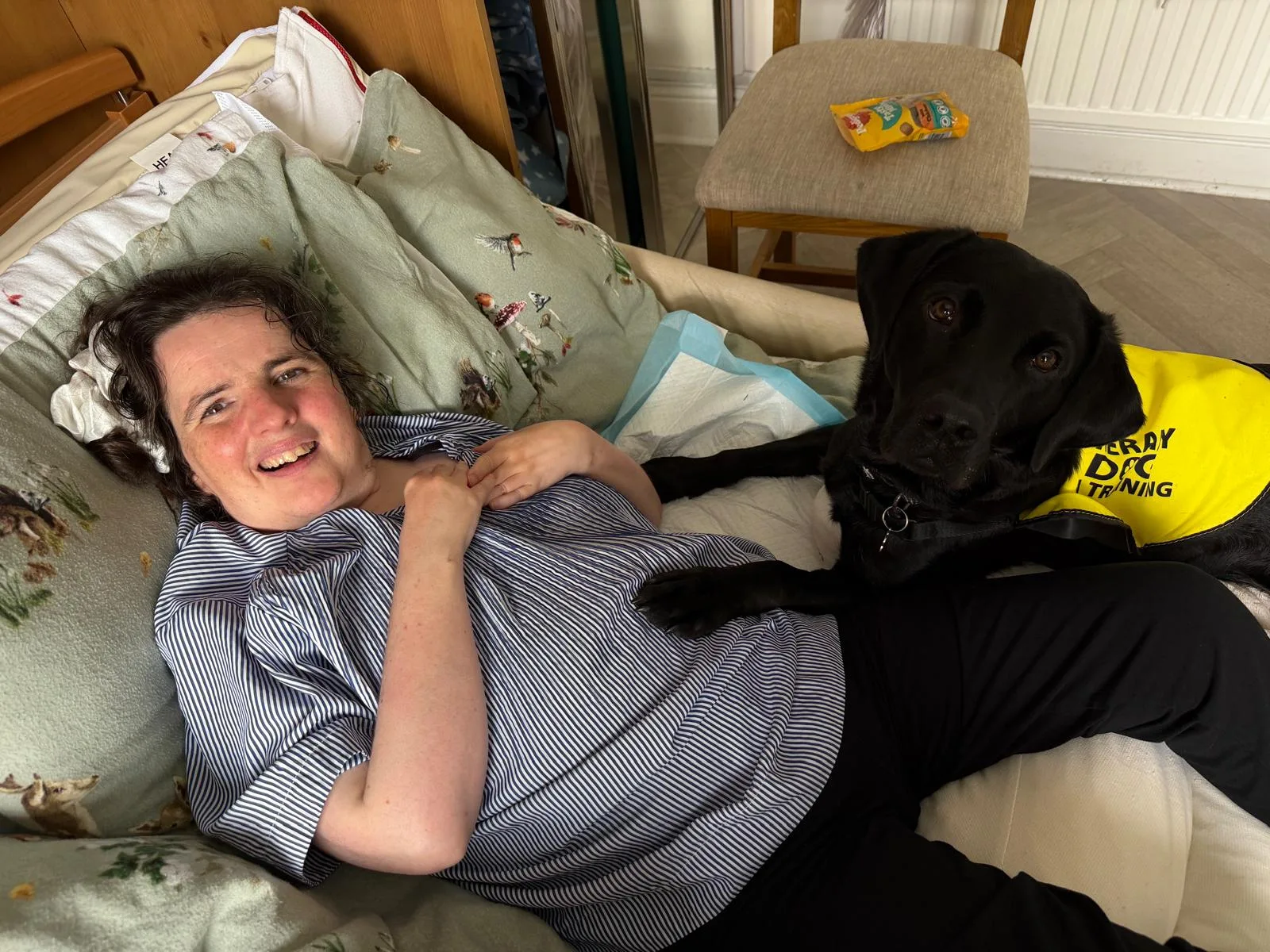 Shadow wearing her therapy dog vest, spending time with someone during a visit.